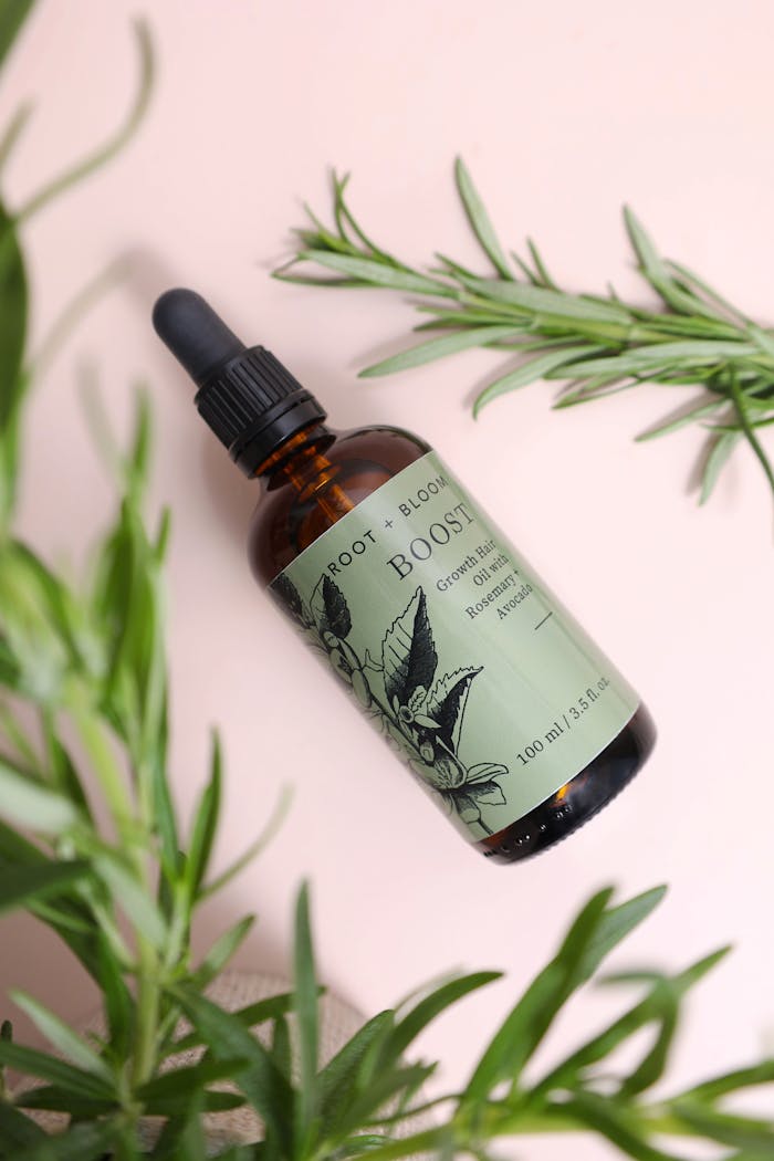 Natural hair growth oil in a glass bottle with botanical elements on a pastel background.